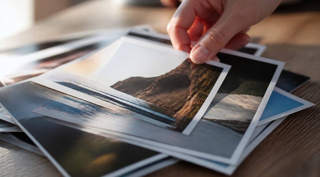 Close-up van fotoprints op een houten tafel tijdens het uitzoeken en rechtleggen
